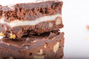 Tasty Pastry Tasty Treats: Closeup on 2 stacked brownies with nuts and chocolate frosting