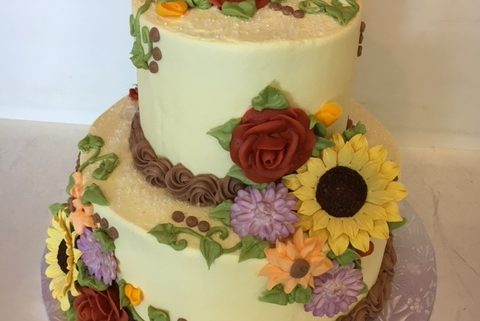 Tasty Pastry Custom Cakes: Two-tier sunflower wedding cake or birthday cake with light green icing & a variety of iced edible flowers