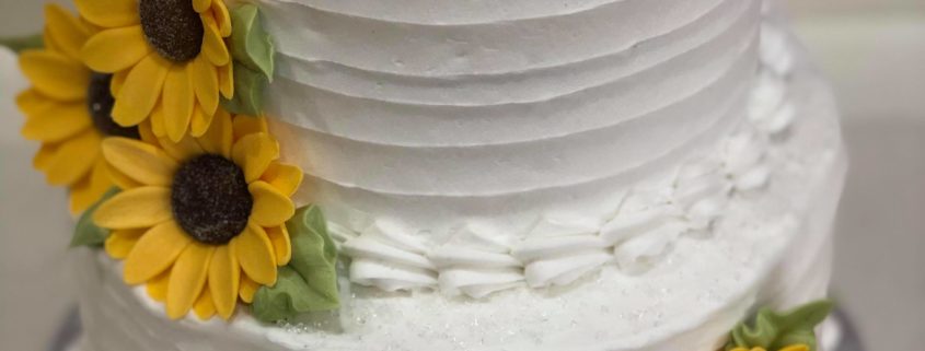 Tasty Pastry Custom Cakes: Two-tier cake with white icing & decorated with edible sugar sunflowers